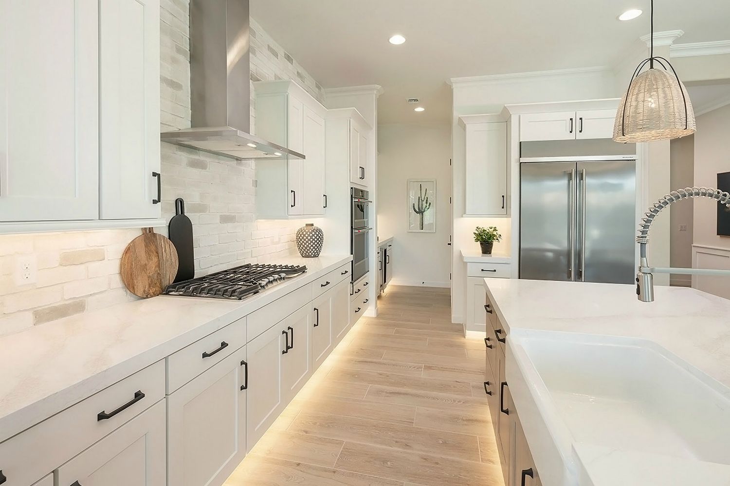 Encanto Residence Six model kitchen with white cabinets, a large island, and built-in appliances
